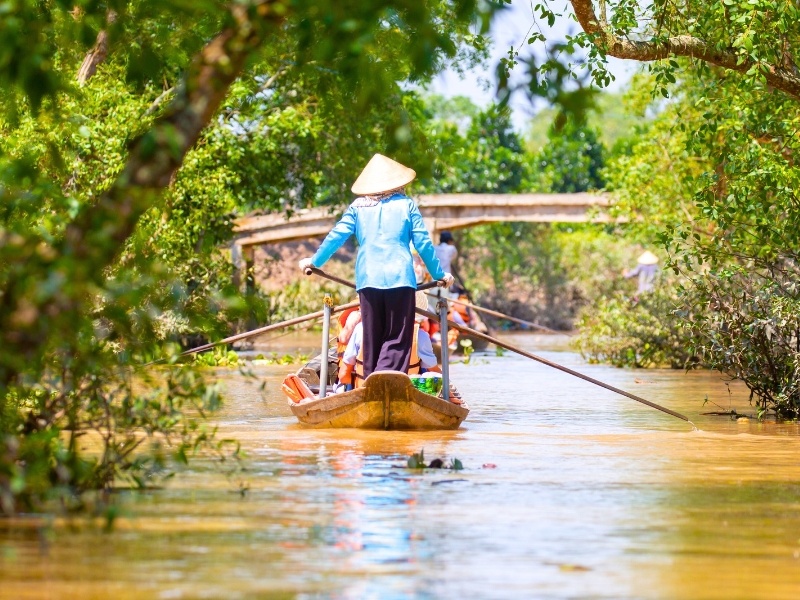 Bootsfahrerin mit Reishut auf einem Kanal im Mekong-Delta