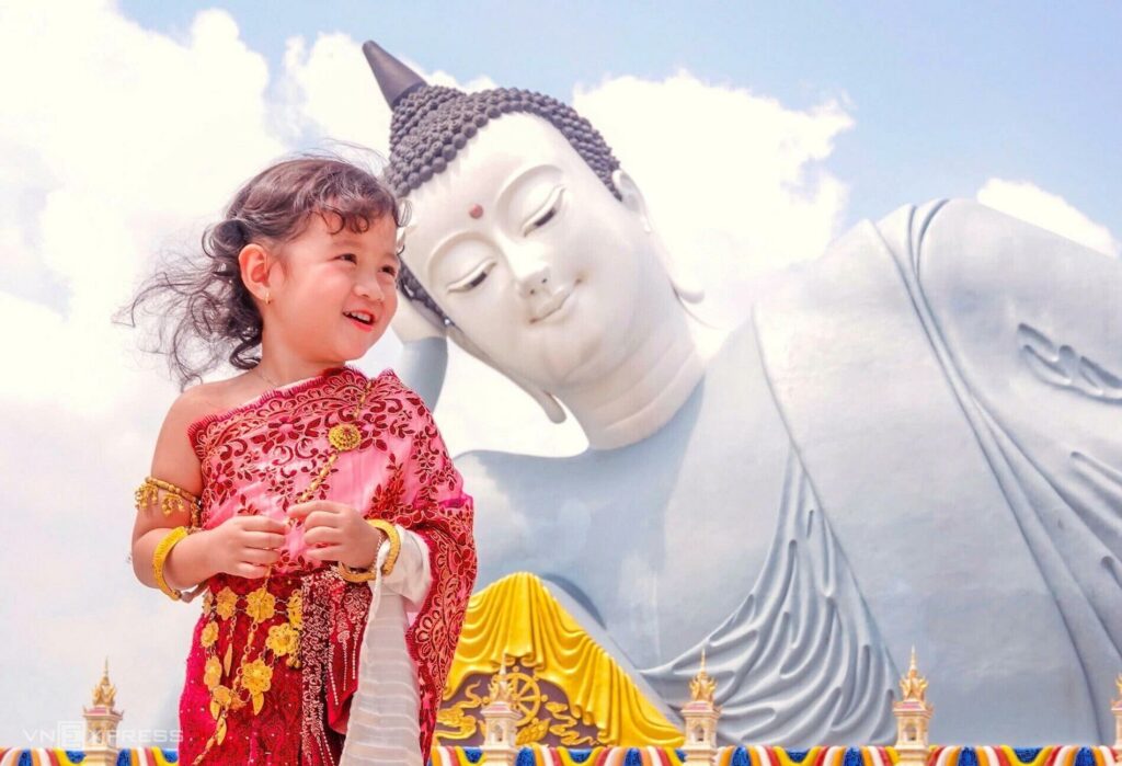 Ein Kind in traditioneller Khmer-Tracht vor der Statue des liegenden Buddha