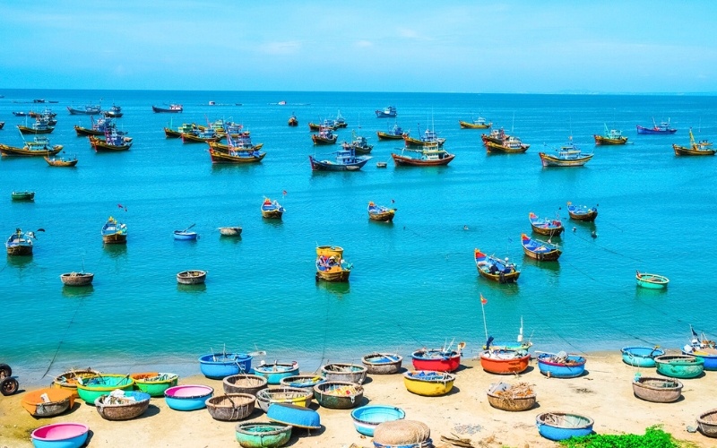 Bunte Fischerboote und Korbboote vor Mui Ne